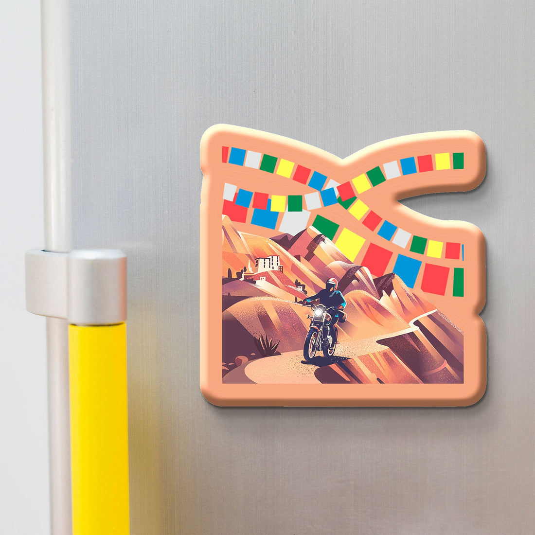 Decorative 'LADAKH' magnet with a motorcycle rider and colorful flags on a metallic surface